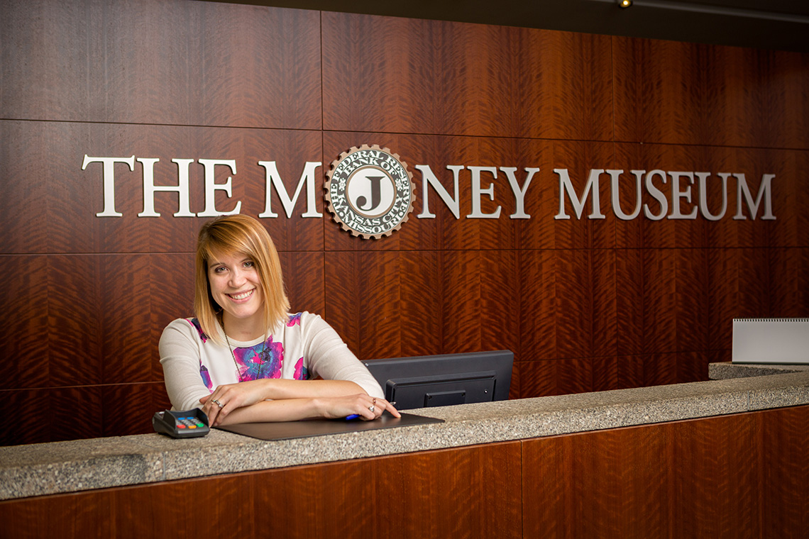 A woman leaning on the visitor's desk at The Money Museum