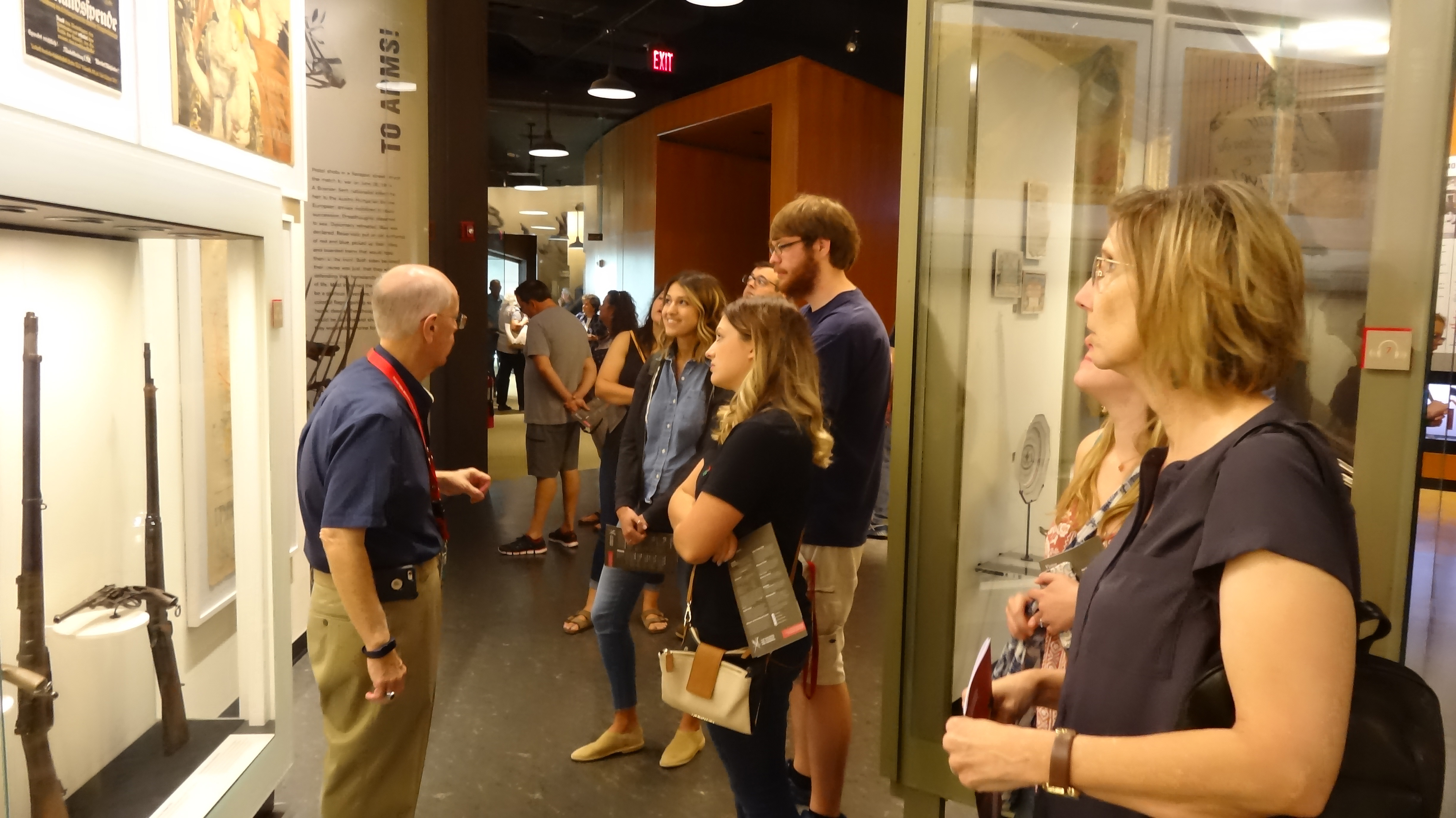 White man giving tour of National World War I Museum exhibits to group of program students.